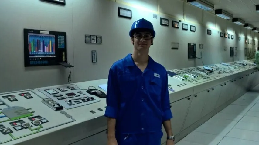 Hamed Abdollahi wearing blue protective workwear and a hard hat inside the control room at Mobarakeh Steel Company